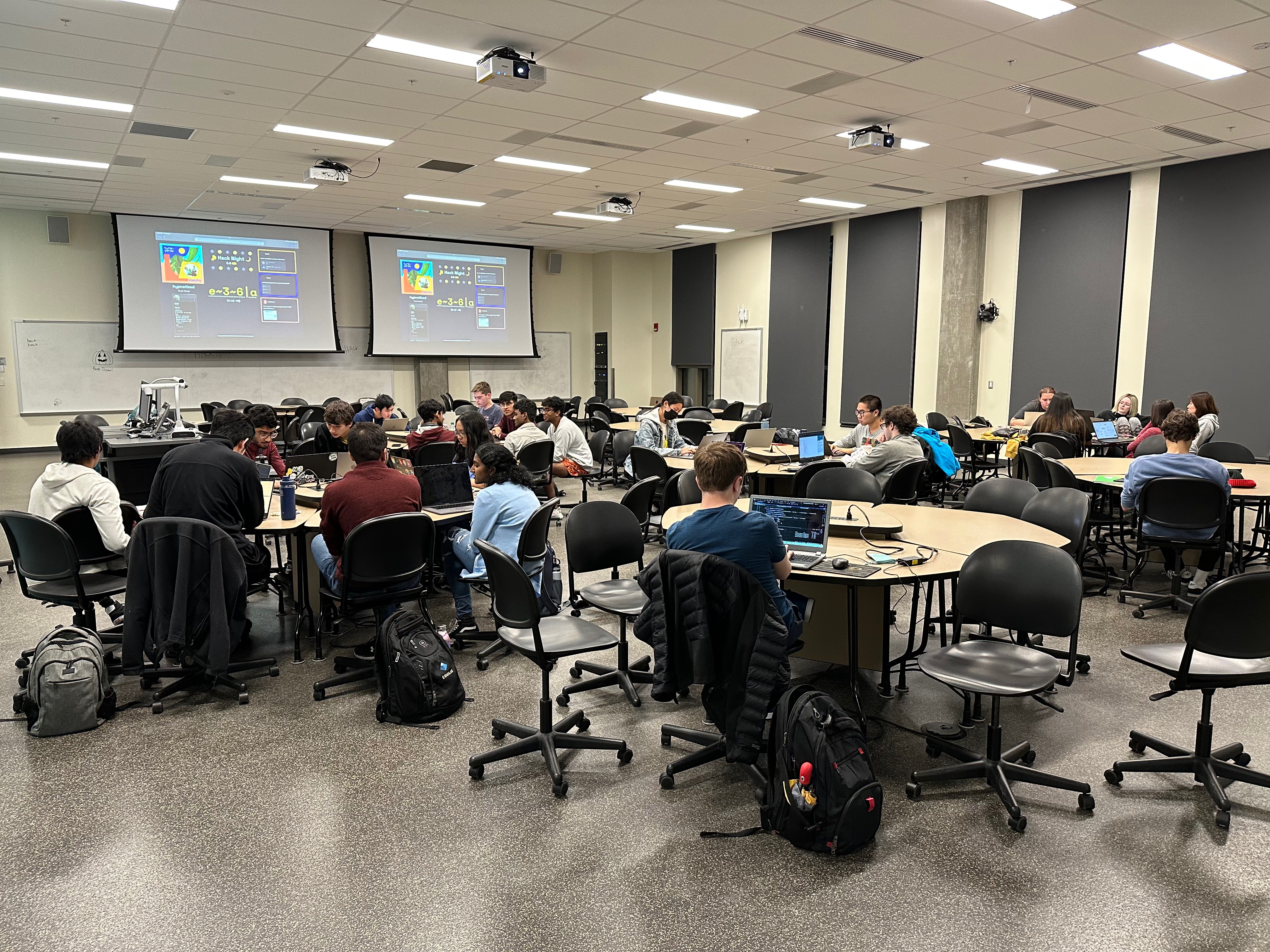 A wide-angle shot of lots of people in a large room all working at tables