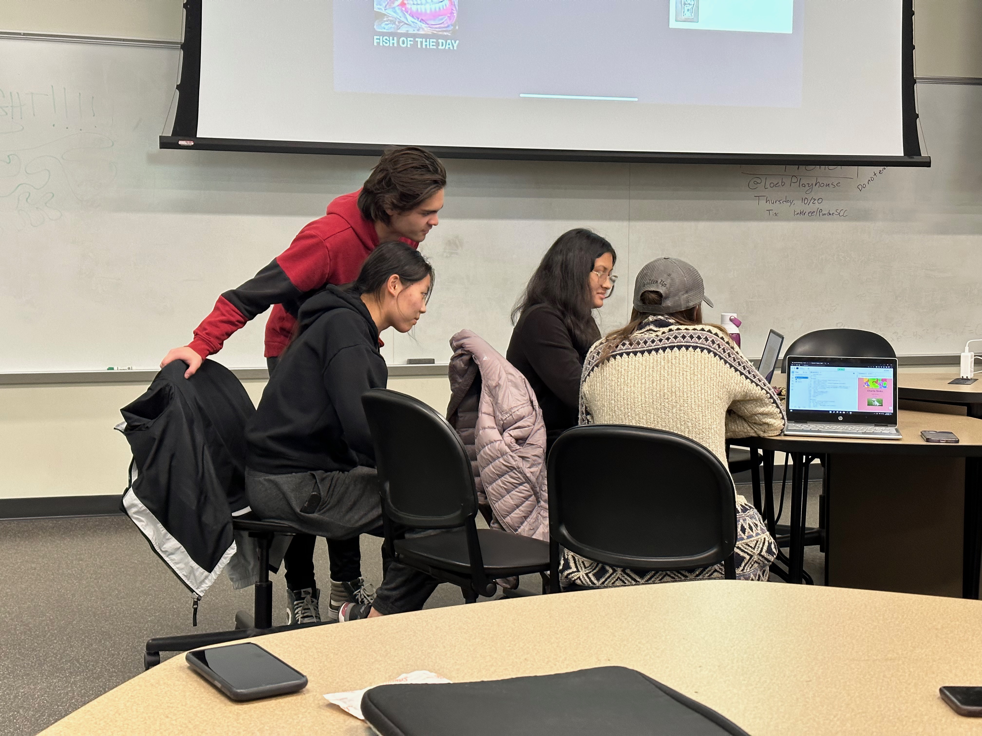 A smaller group of people huddled around a computer at a table