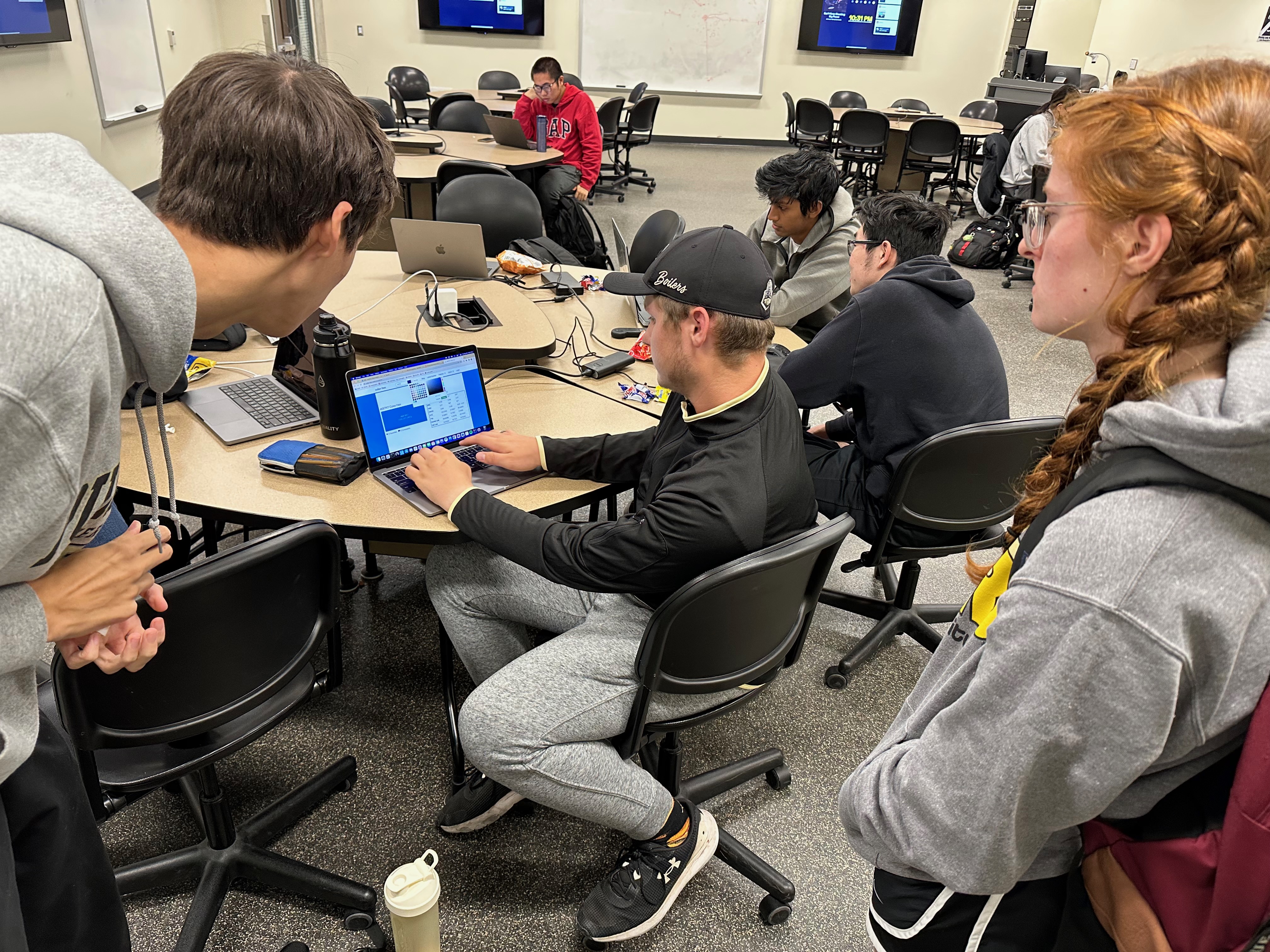 Three people huddled around a table. The person in the middle is at a
computer, everyone else is looking at what they are
doing.